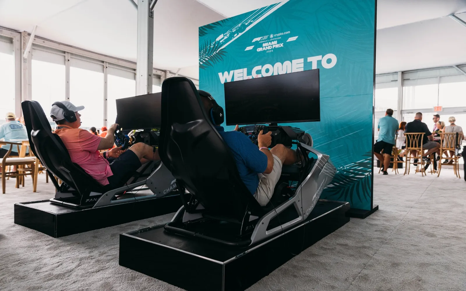 Guests using F1 racing simulators inside F1 Paddock Club hospitality lounge